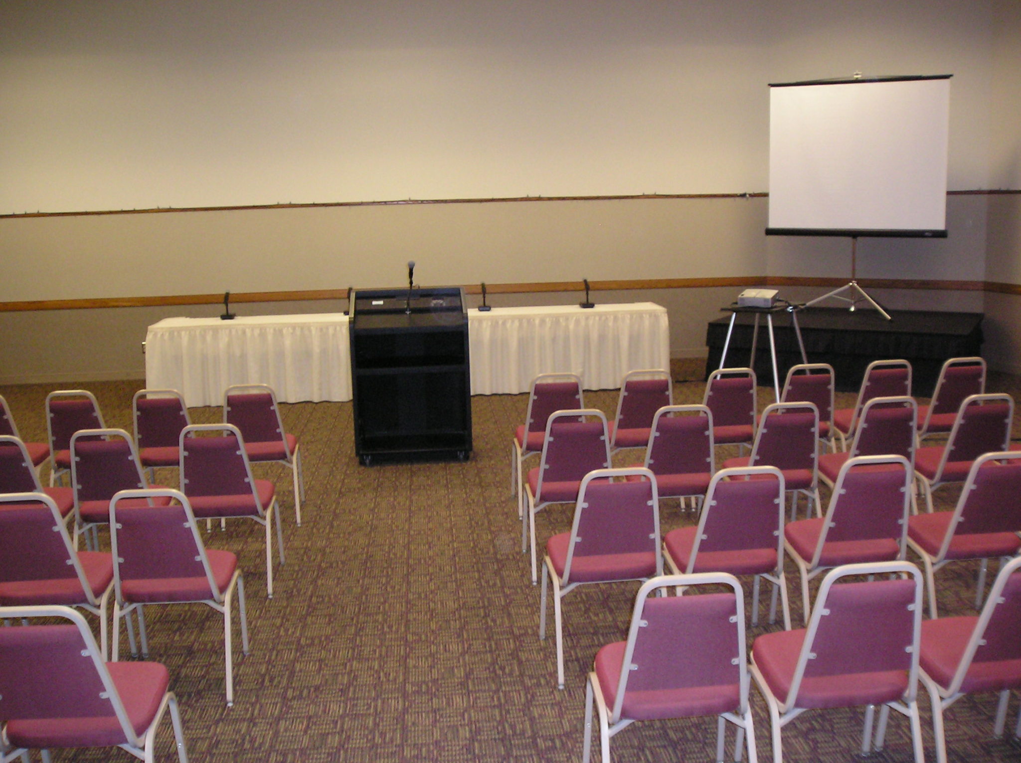 chairs set up for a meeting in front of a head table and white board