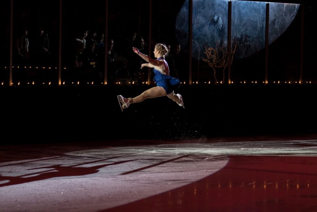 Figure skater doing a jump at annual ice show. 