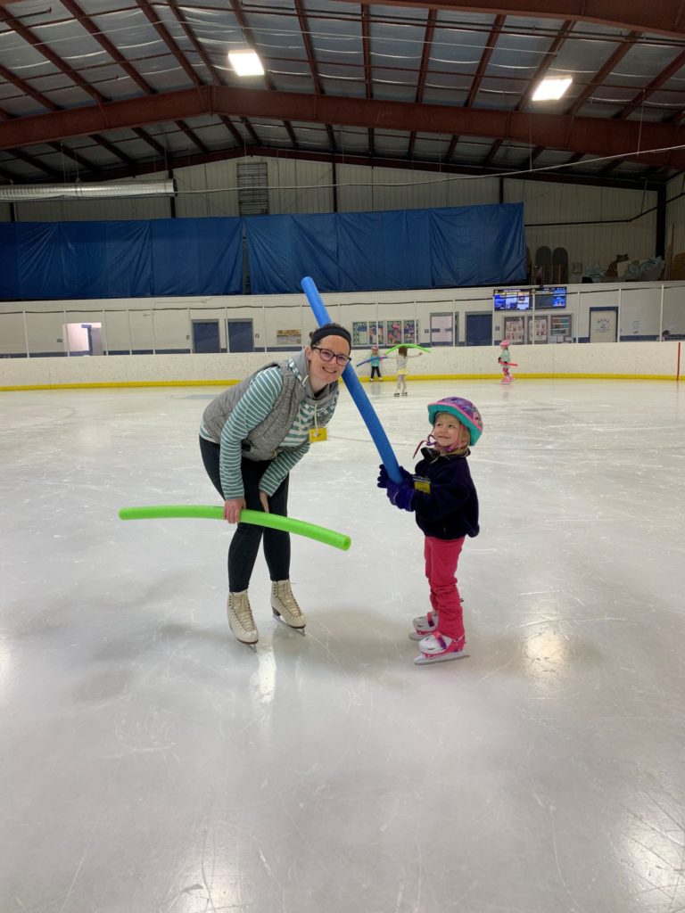 Young skater and instructor having fun on the ice. 