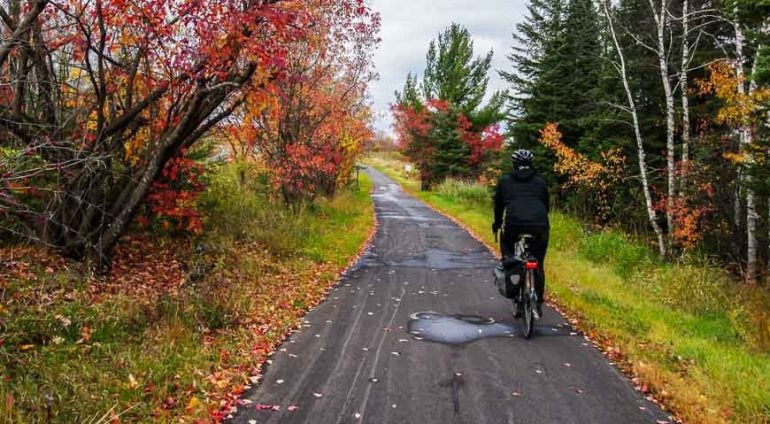 bicycle rider on a paved path in the woods during the fall with vibrant colors